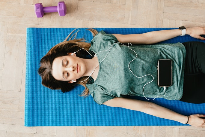 Frau liegt auf Yogamatte während Progressiver Muskelentspannung