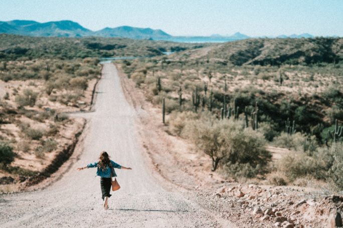 Frau in der Wüste geht auf einer Straße und macht Gehmeditation