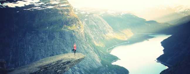 Die zweite der Meditationsarten ist Yoga, Frau macht Yoga auf dem Berg mit Blick auf einen schönen See