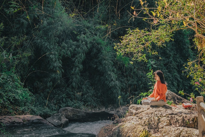 Frau in Meditation auf Felsen in der Natur