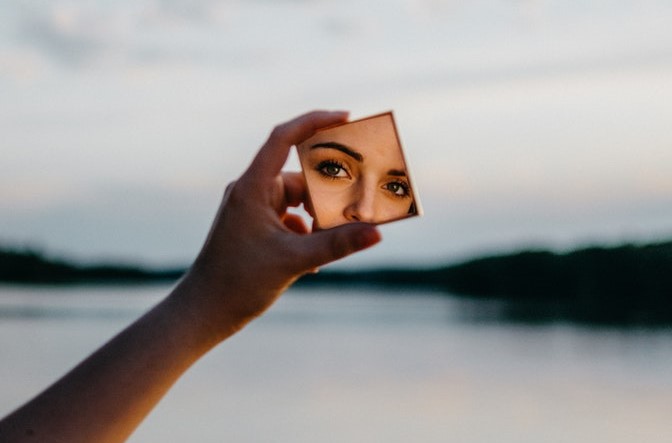 Selbstreflexion Frau im Spiegel mit Wasser im Hintergrund querformat