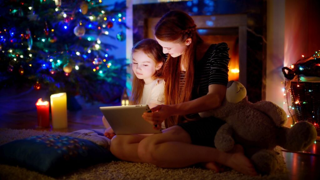 Weihnachtsgeschichte fürs Herz Beitragsbild Mutter liest Tochter eine Weihnachtsgeschichte am Weihnachtbaum vor