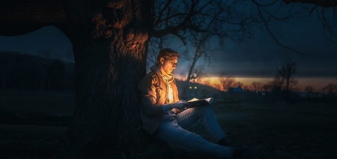 Junge unter Baum liest in Buch über Fantasiereisen