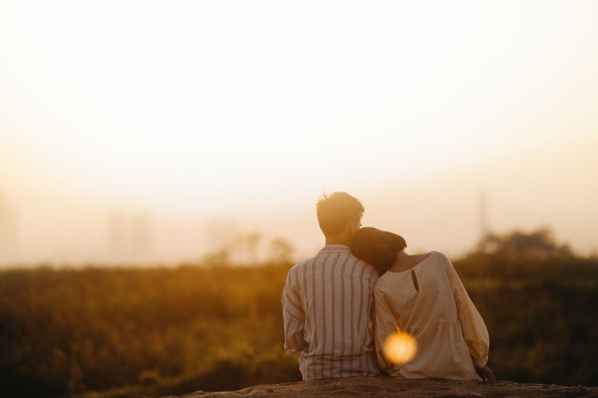 Ein junges Paar spricht über tiefgründige Fragen und schaut in das Abendlicht